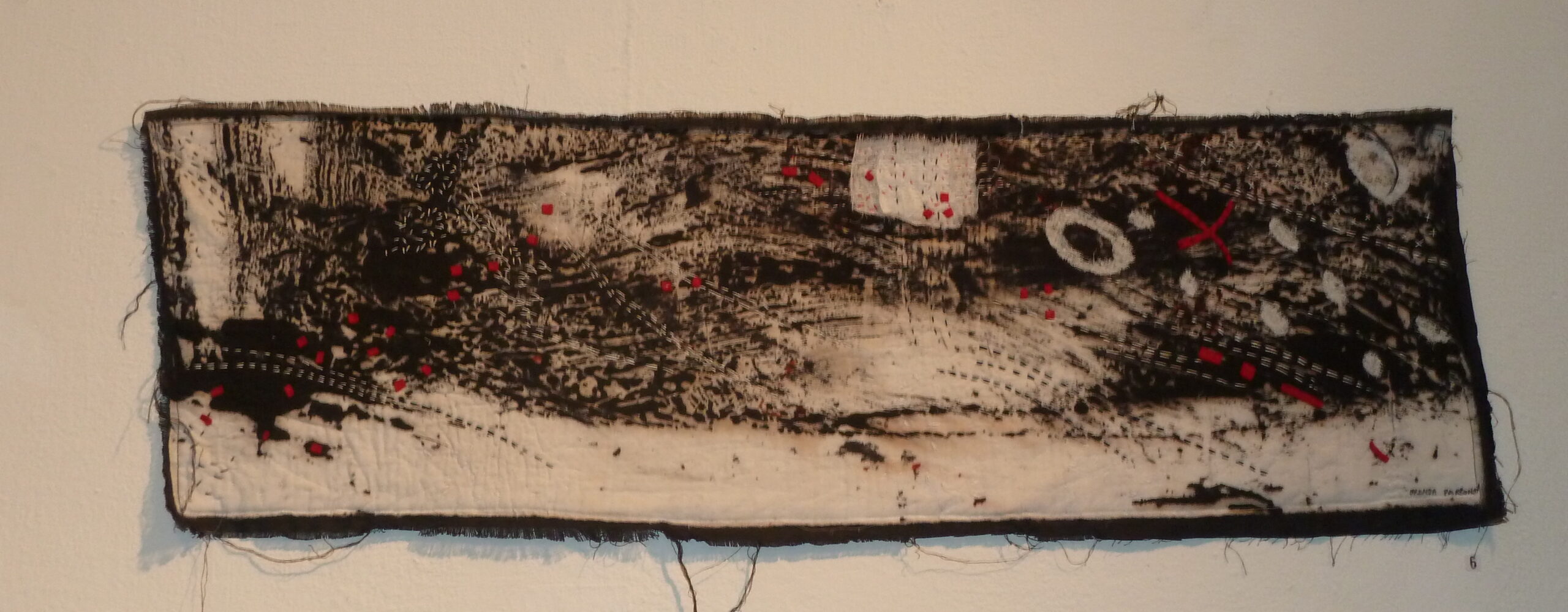Long black and white monoprint with textured marks, pale paper and small red stitched accents