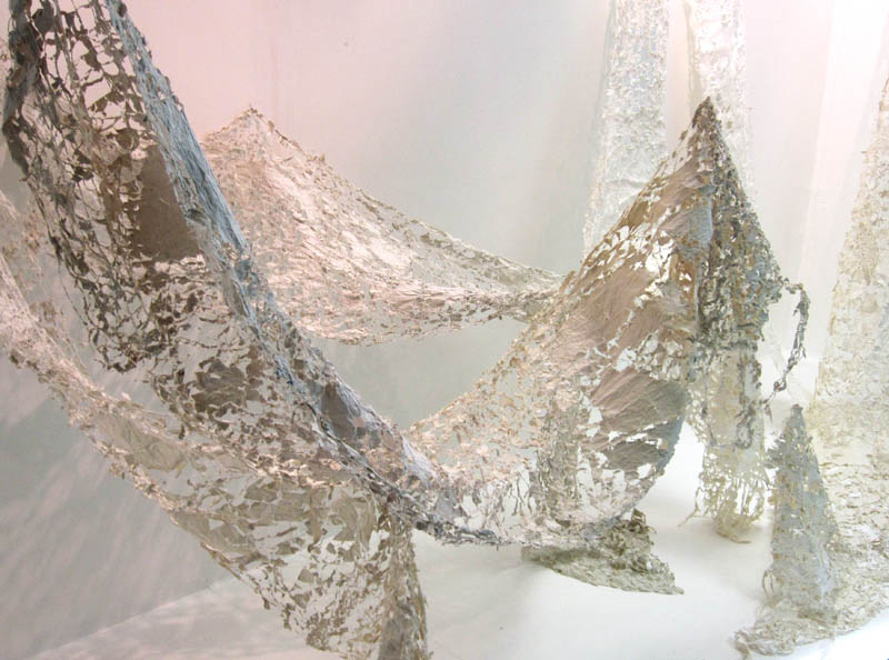 Delicate paper lace forms suspended in a softly lit space